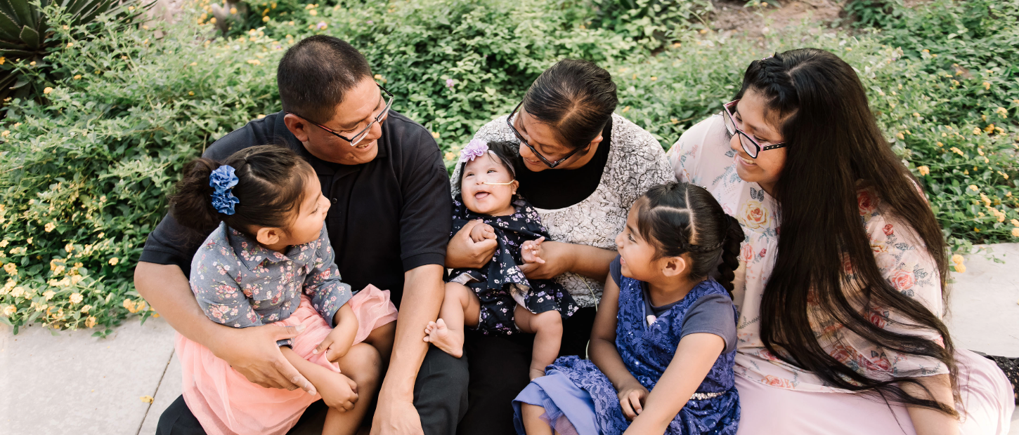 Family sitting on ground with 3 kids