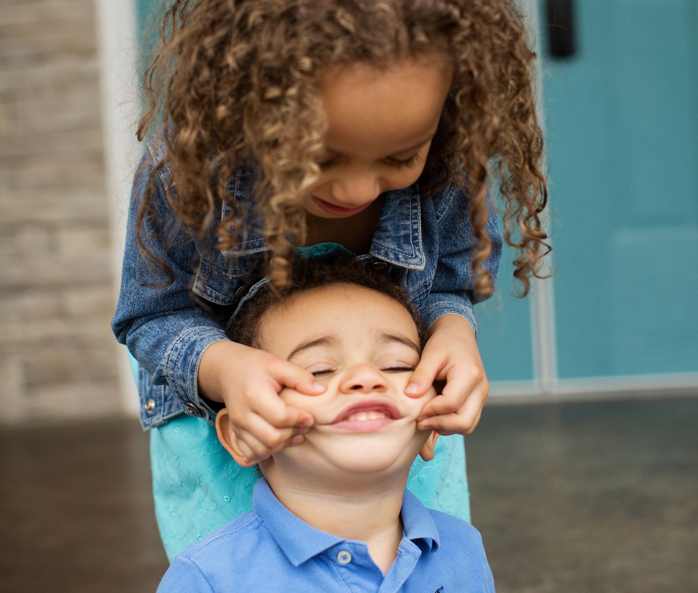 Sister pinching brother's cheeks