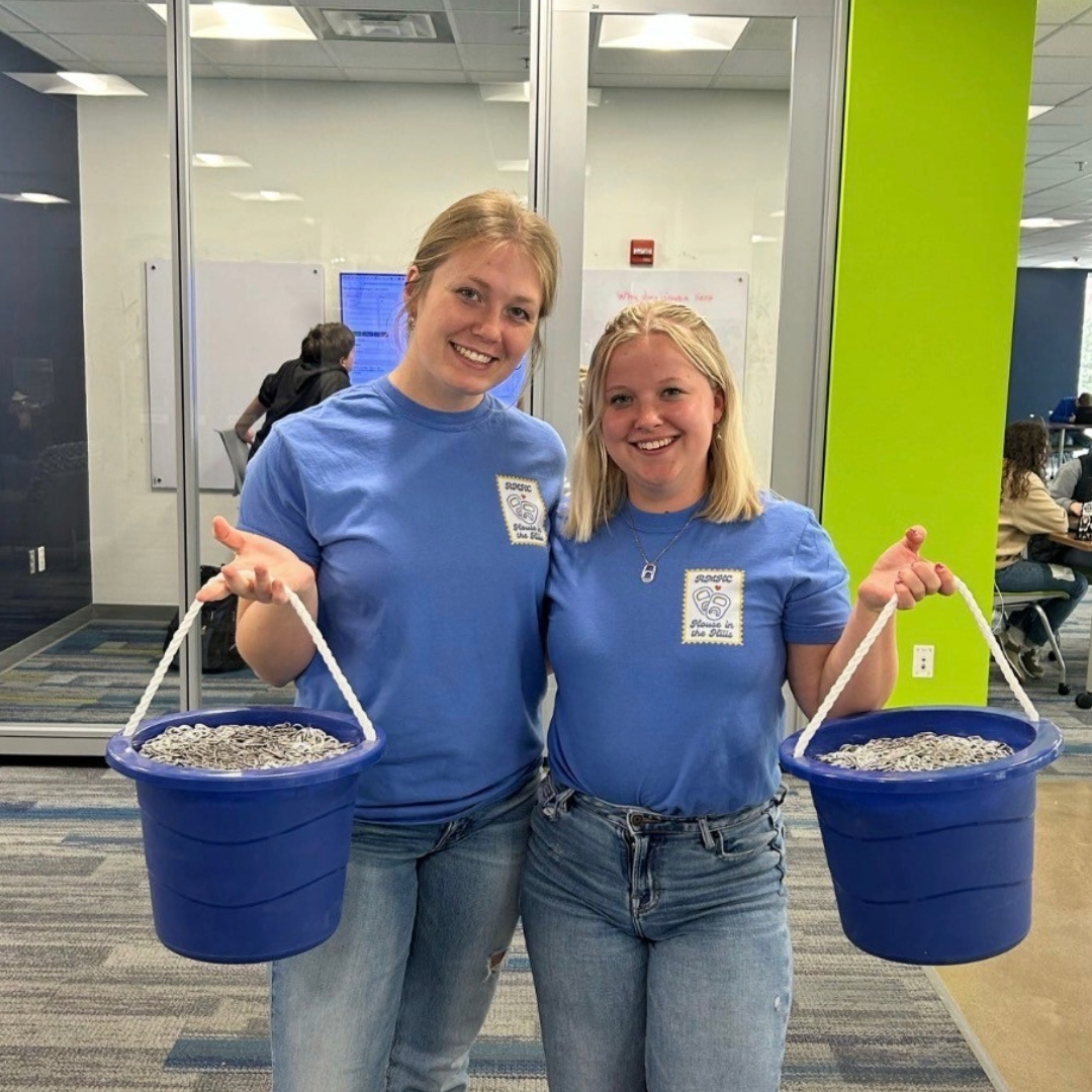 Young women holding buckets of pop tabs